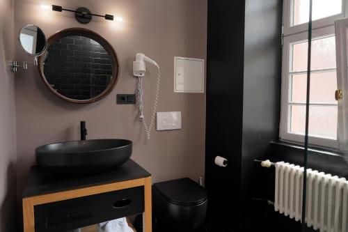 a bathroom with a black sink and a mirror at Wohnkultur - DSIGNIO Ladenburg Digital Hotel in Ladenburg