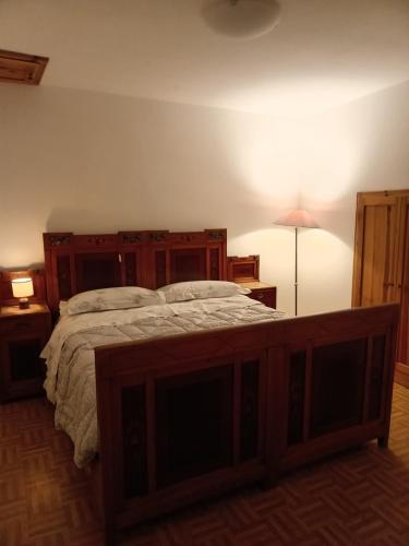 a bedroom with a large bed with a wooden frame at Appartamento Conti Schreck in Baselga di Pinè
