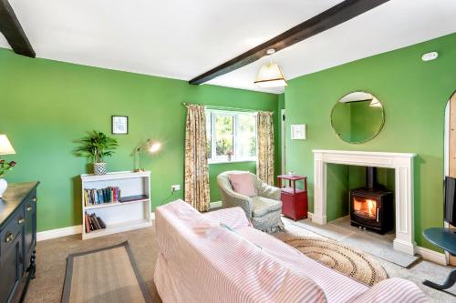 a living room with green walls and a fireplace at Chantry Cottage - Newby Hall, Ripon, North Yorkshire in Copt Hewick