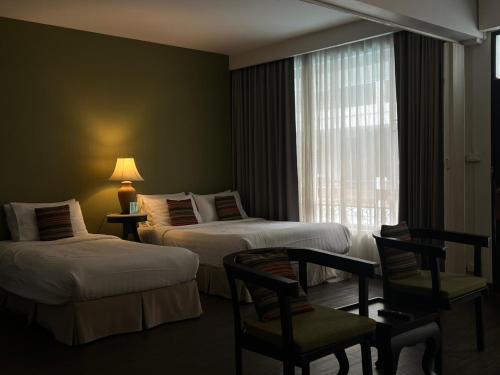 a hotel room with two beds and a window at Fullrich Lanna Suite in Chiang Mai