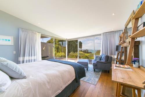 a bedroom with a large bed and a large window at Waiheke Luxury Blue and Green Rooms in Ostend