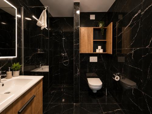a black tiled bathroom with a toilet and a sink at Rivapark in Dunajská Streda