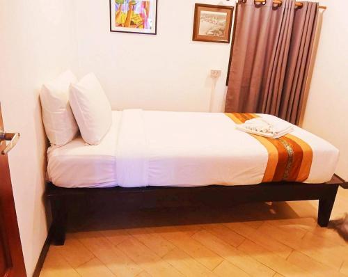 a bed with white sheets and pillows in a room at Chedi Home in Chiang Mai