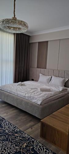 a large bed in a bedroom with a chandelier at AMARANT hotel in Baysun