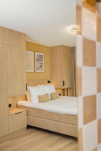 a bedroom with a large bed with white pillows at Hotel Riet I Kloeg Collection in Koudekerke
