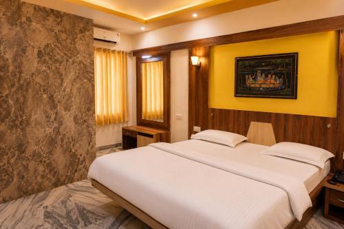 a bedroom with a large bed and a yellow wall at Hotel kabras' inn in Mount Ābu