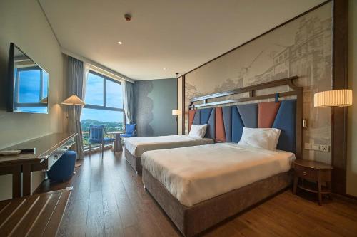a hotel room with two beds and a desk at Apec Mandala Ocean Retreat- Mui Ne in Mui Ne