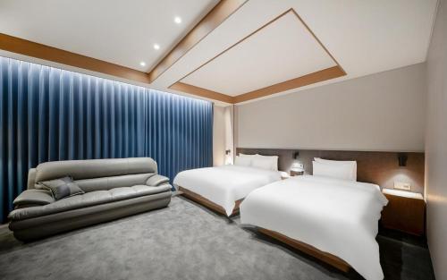 a hotel room with two beds and a couch at Gwangju The IN Hotel in Gwangju