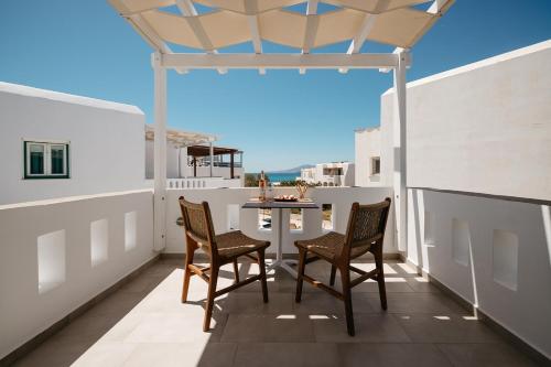a patio with two chairs and a table on a balcony at Iades Studios & Apartments in Agia Anna Naxos