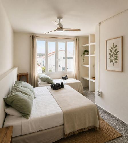 a bedroom with two beds and a large window at Hotel S'Algaret in Fornells