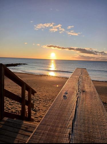 a wooden pier on the beach with the sun setting at Tropical Duplex : Bord de mer + Piscine in Frontignan