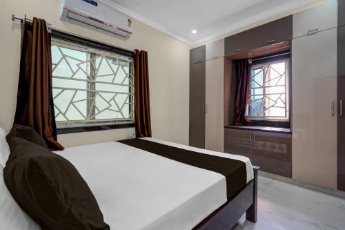 a bed in a room with two windows and a bed sidx sidx sidx at Hotel O The Royal Guest Rooms in Vijayawāda