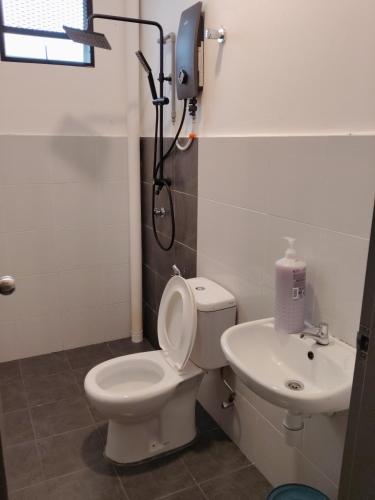 a bathroom with a toilet and a sink at Teratak Saharah Homestay in Port Dickson