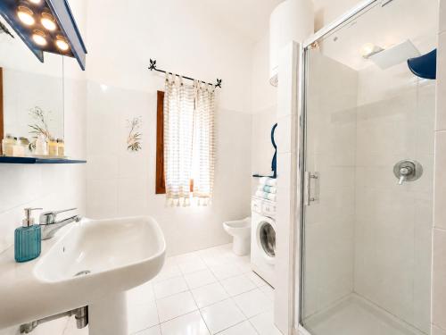 a white bathroom with a sink and a shower at Piazzetta Dei Pini Two Bedroom Apartment 100 m from the Beach in Baja Sardinia