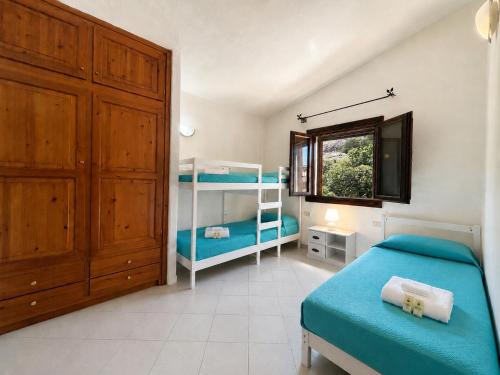 a bedroom with two bunk beds and a window at Piazzetta Dei Pini Two Bedroom Apartment 100 m from the Beach in Baja Sardinia