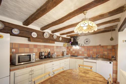 a kitchen with white cabinets and a wooden table at La Gaubertière in Saint-Paul-du-Bois