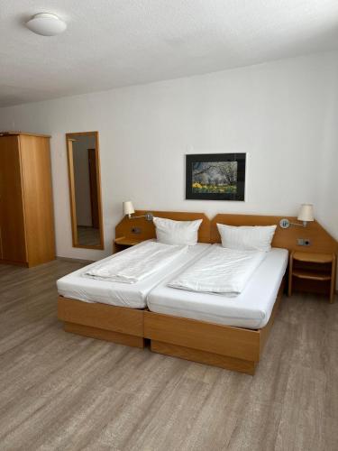 a bedroom with a large bed with white sheets at Hotel Kaiserpfalz in Fritzlar