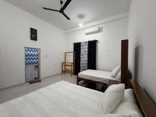 a bedroom with two beds and a desk in it at Yala Dream Guest House in Tissamaharama