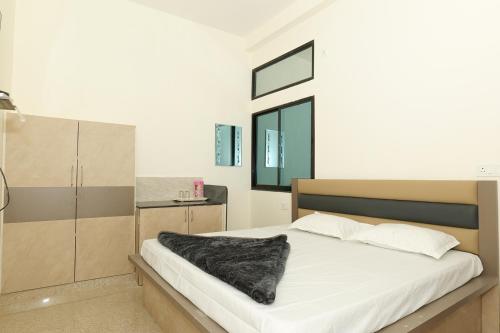 a bedroom with a bed with a black blanket on it at Hotel Deeksha in Mandlā