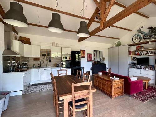 a kitchen and living room with a wooden table and chairs at ATELIER Gîte Cahors in Pradines