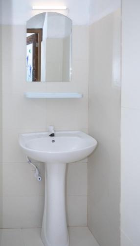 a white bathroom with a sink and a mirror at Pavani Villa Kandy in Peradeniya