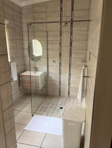 a bathroom with a shower with a toilet and a sink at Grey Corner Guesthouse in Postmasburg