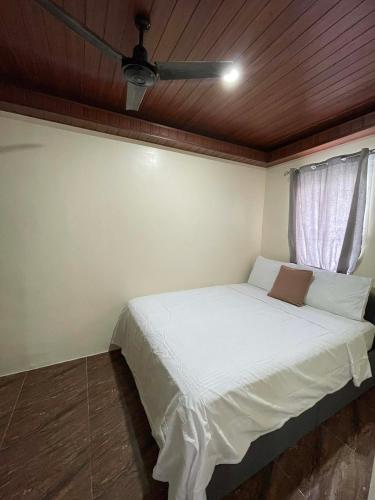 ein Schlafzimmer mit einem weißen Bett und einem Deckenventilator in der Unterkunft Brians Palace in Tagum