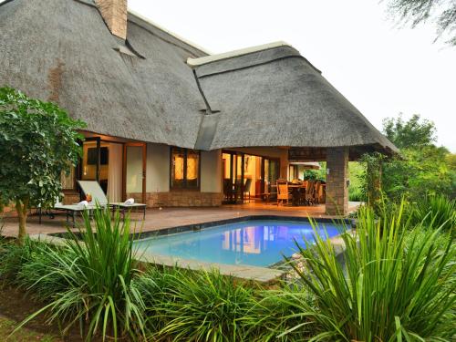 a house with a thatched roof and a swimming pool at Hluhluwe Lodge by ANEW in Hluhluwe