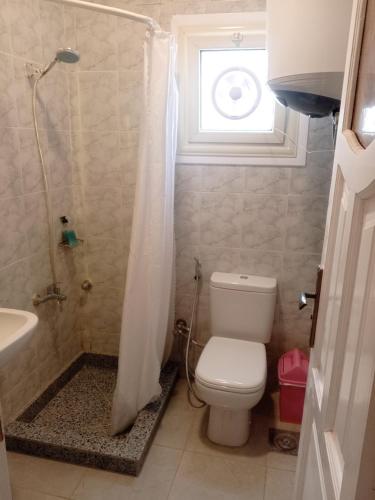a bathroom with a toilet and a shower with a window at Halfmoon House- fully air-conditioned- مكيف بالكامل in El Alamein
