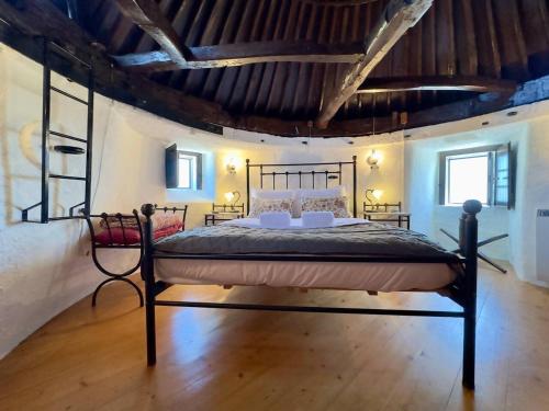 a bedroom with a black bed in a room at Moinhos Da Guimaroa in Cadafais