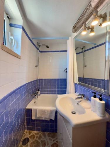 a blue tiled bathroom with a sink and a mirror at Moinhos Da Guimaroa in Cadafais