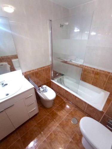 a bathroom with a shower and a toilet and a sink at Apartamento Playa Foz in Foz