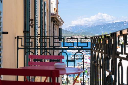 a table and chairs on a balcony with a view of the water at Hotel POZZO DI BORGO in Ajaccio