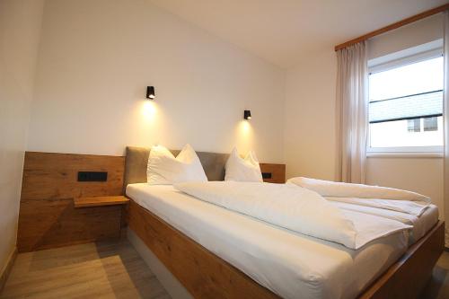 a bedroom with a bed with white sheets and a window at Apartments Luidold in Schladming