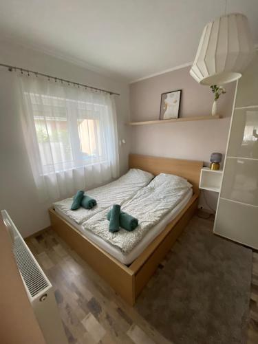 a bedroom with a bed with two green pillows on it at Deák Apartman Gárdony in Gárdony