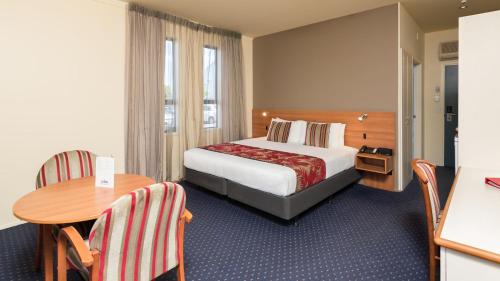 a hotel room with a bed and a table at Heartland Hotel Auckland Airport in Auckland