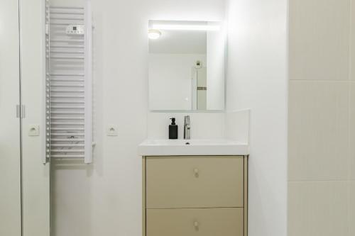 a white bathroom with a sink and a mirror at Le Cocon d'Achères in Achères
