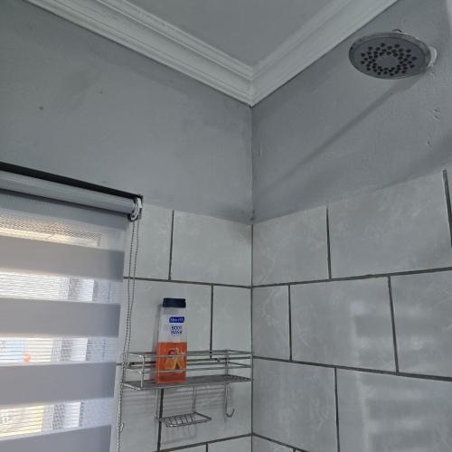 a bathroom with white tiled walls and a shower at The Family Room in Krugersdorp