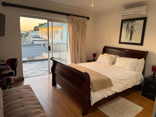 a bedroom with a large bed and a balcony at Golden Feathers Lodge in Cape Town