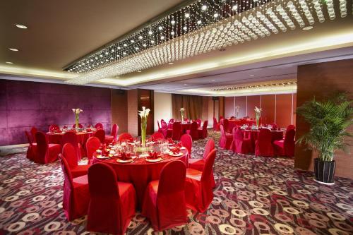 a banquet room with red tables and chairs and a stage at Grand Park Wuxi in Wuxi