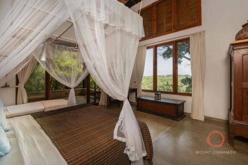 a bedroom with a canopy bed with white curtains at Mount Cinnamon Mirissa in Mirissa
