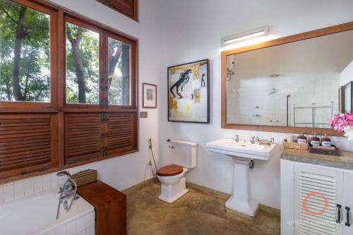 a bathroom with a toilet and a sink and a window at Mount Cinnamon Mirissa in Mirissa
