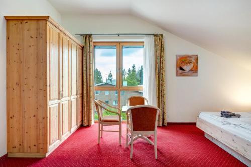 a bedroom with a bed and two chairs and a window at Wohnung direkt an der Skipiste in Feldberg