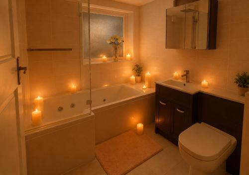 a bathroom with a tub and a toilet and candles at Bliss Home in Harrow on the Hill