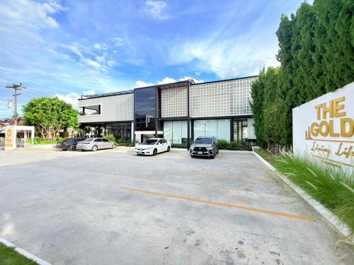 a building with two cars parked in a parking lot at The Gold Living Life in Thung Song