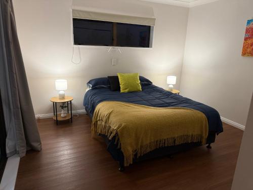 a bedroom with a bed with a yellow pillow on it at Otaihanga Getaway in Paraparaumu