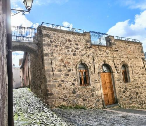 an old stone building with a wooden door and a bridge at Molinu in Santu Lussurgiu