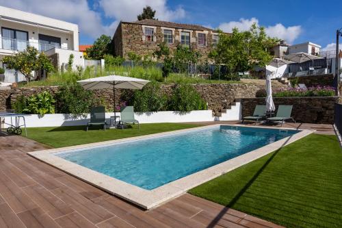 a swimming pool in a yard with chairs and an umbrella at Casa Dona Edite Guesthouse Douro in Vilarinho de Cotas