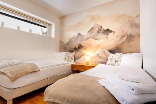 two beds in a bedroom with a mural of mountains at RIVER Apartment in Andermatt