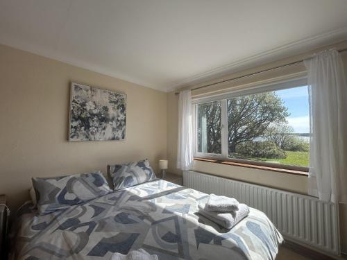 a bedroom with a bed and a large window at Waterside Cottage, Cashel in Galway